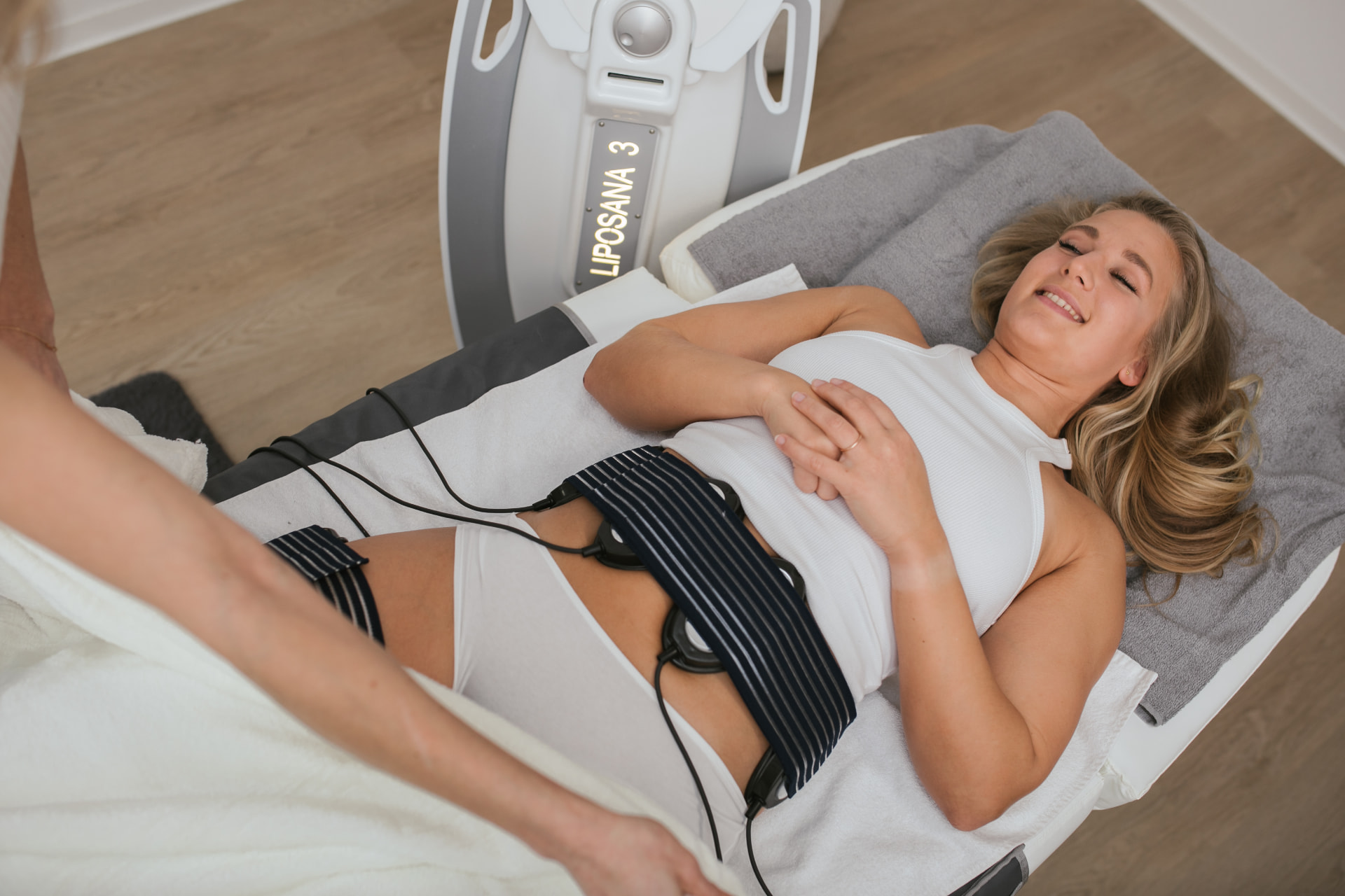 Liposana 3+ Behandlung: Klientin mit Elektrodengurt am Gerät bei Beauty Artistry Villingen